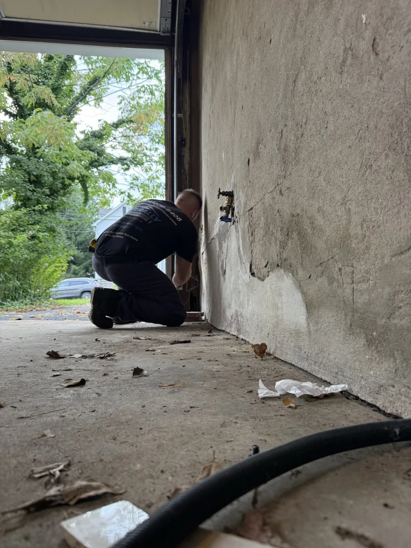 Roni kneeling beside the track of an open garage door