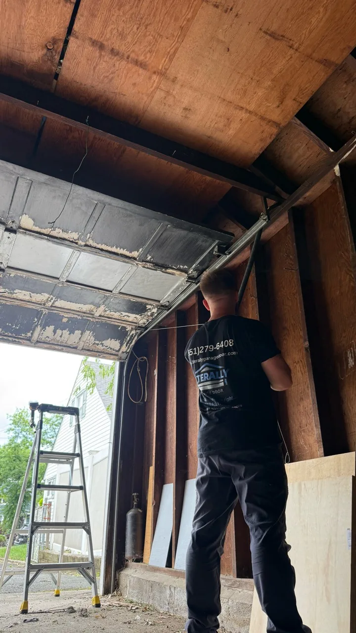 Roni in a Literally Garage Door shirt working beside the track of a raised garage door