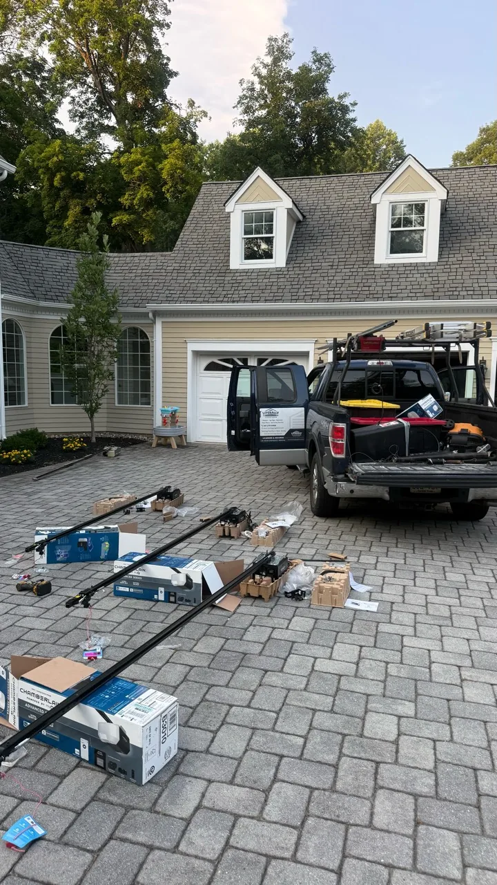 Literally Garage Door service truck with opener boxes, rails and hardware laid out in a driveway